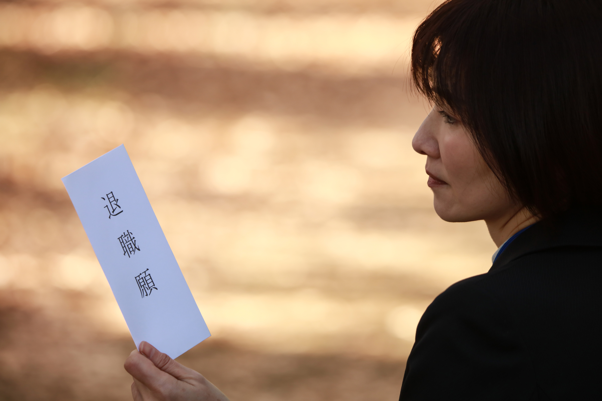 退職届を見つめながら悩んでいる女性