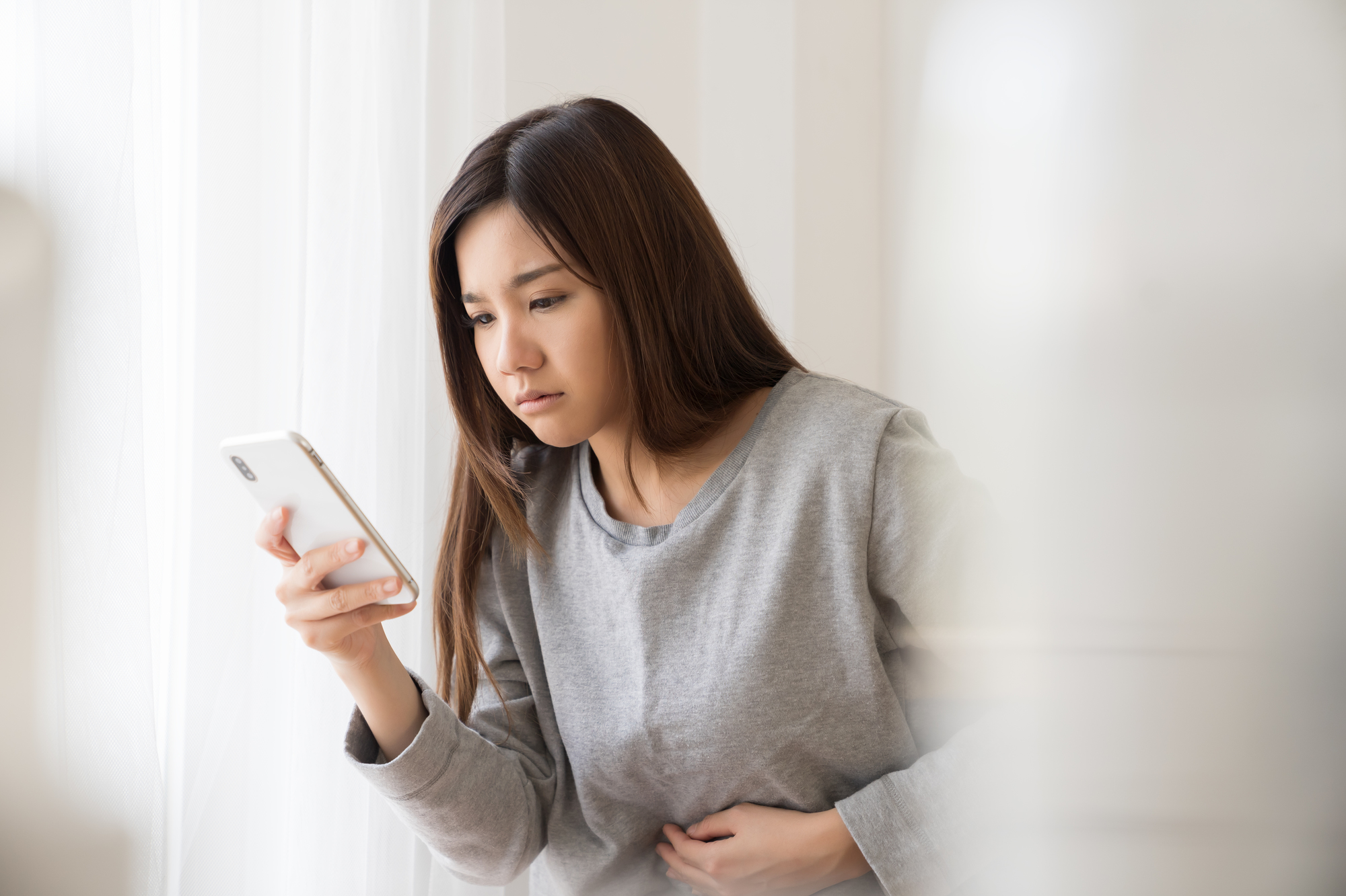 具合が悪そうに携帯を見ている女性の様子
