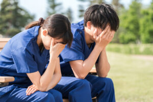 公園のベンチに座り落ち込む看護師（絶望）